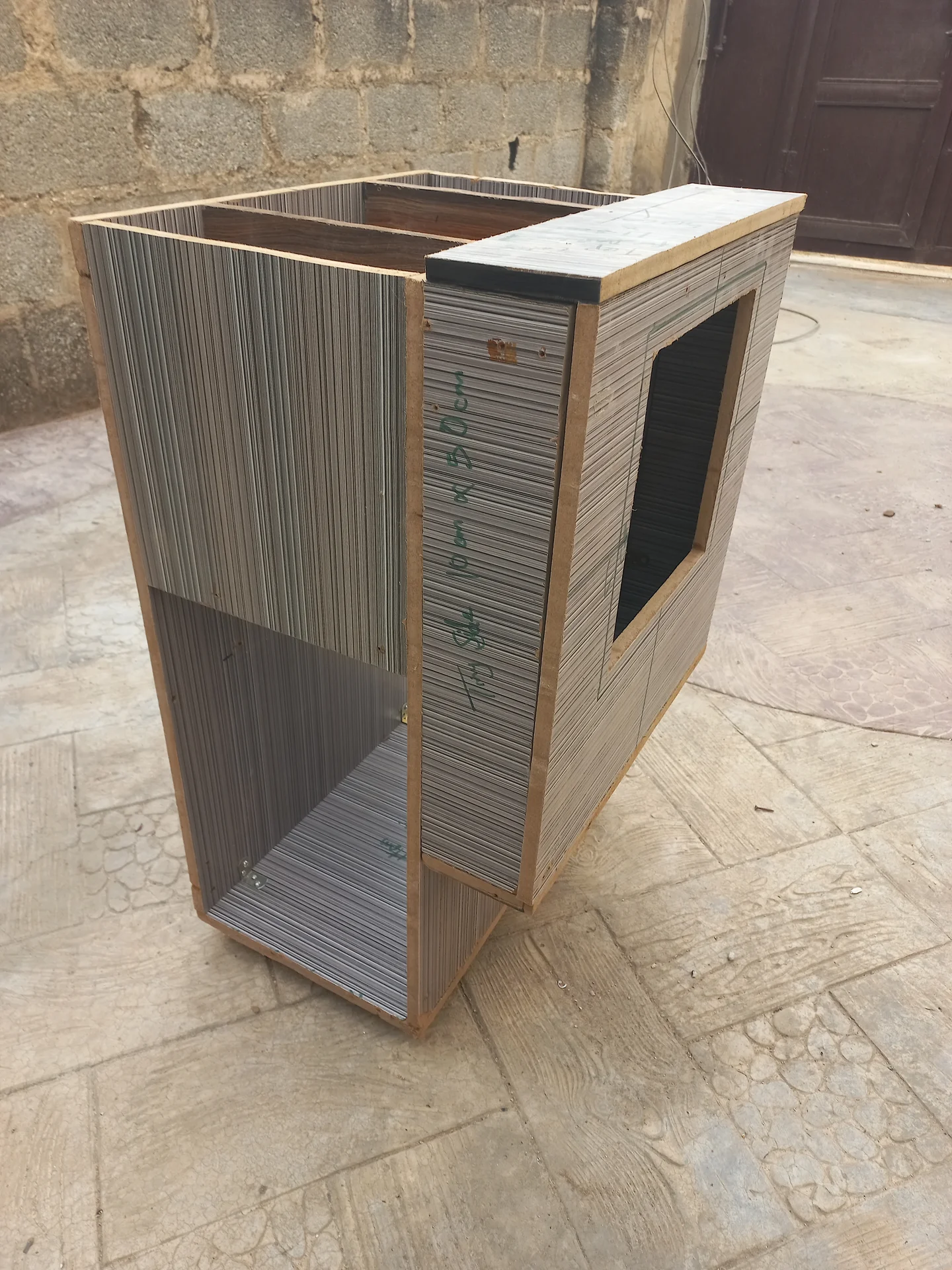 Three-quarter angled exterior view of the bin showing the rectangular cutout on the front panel and a black-painted panel beginning to appear at the top