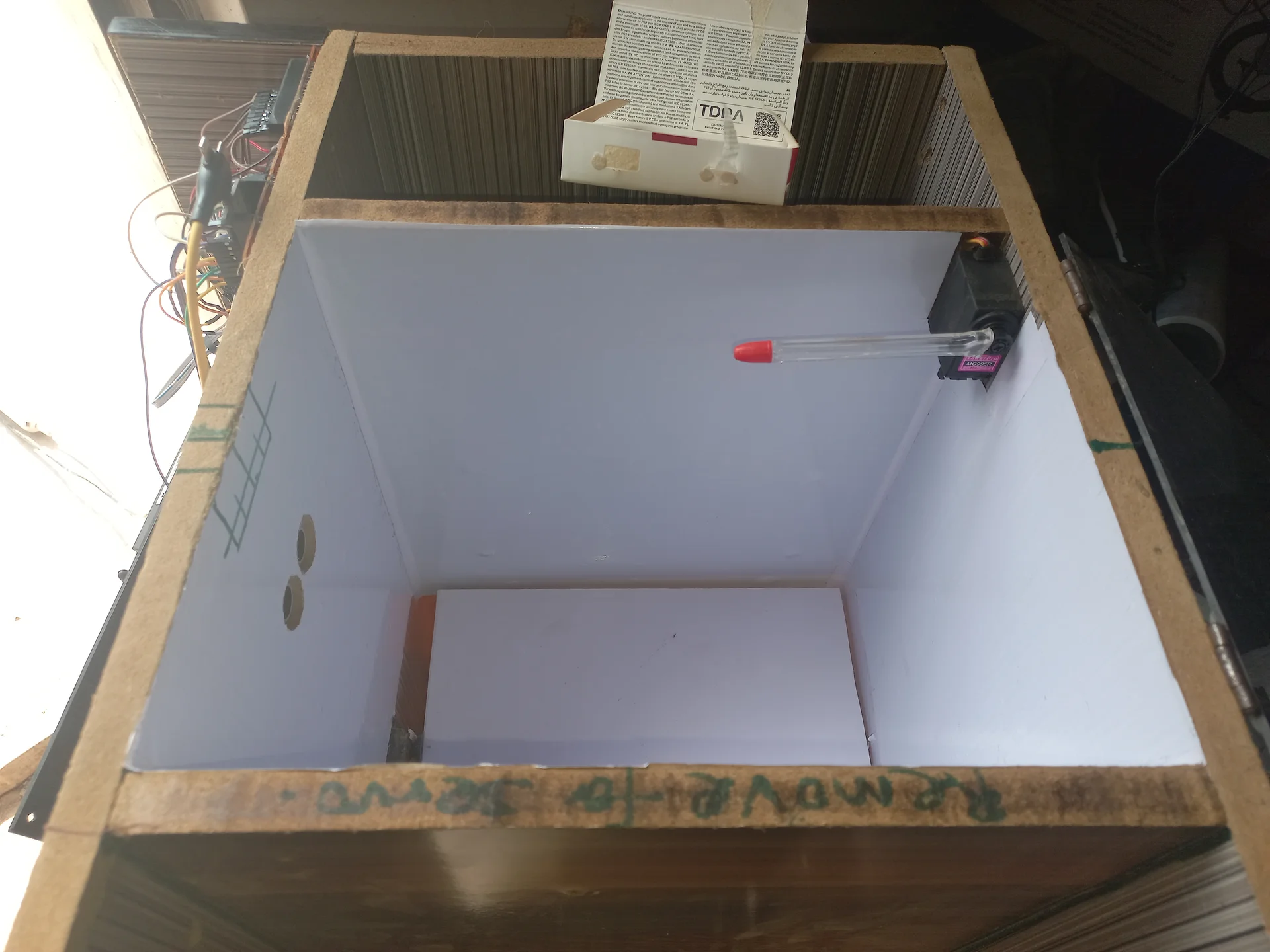 Top-down view into the bin interior showing the sorting tray panel flat in its resting position, with the servo motor on the right wall and ultrasonic sensors on the far wall