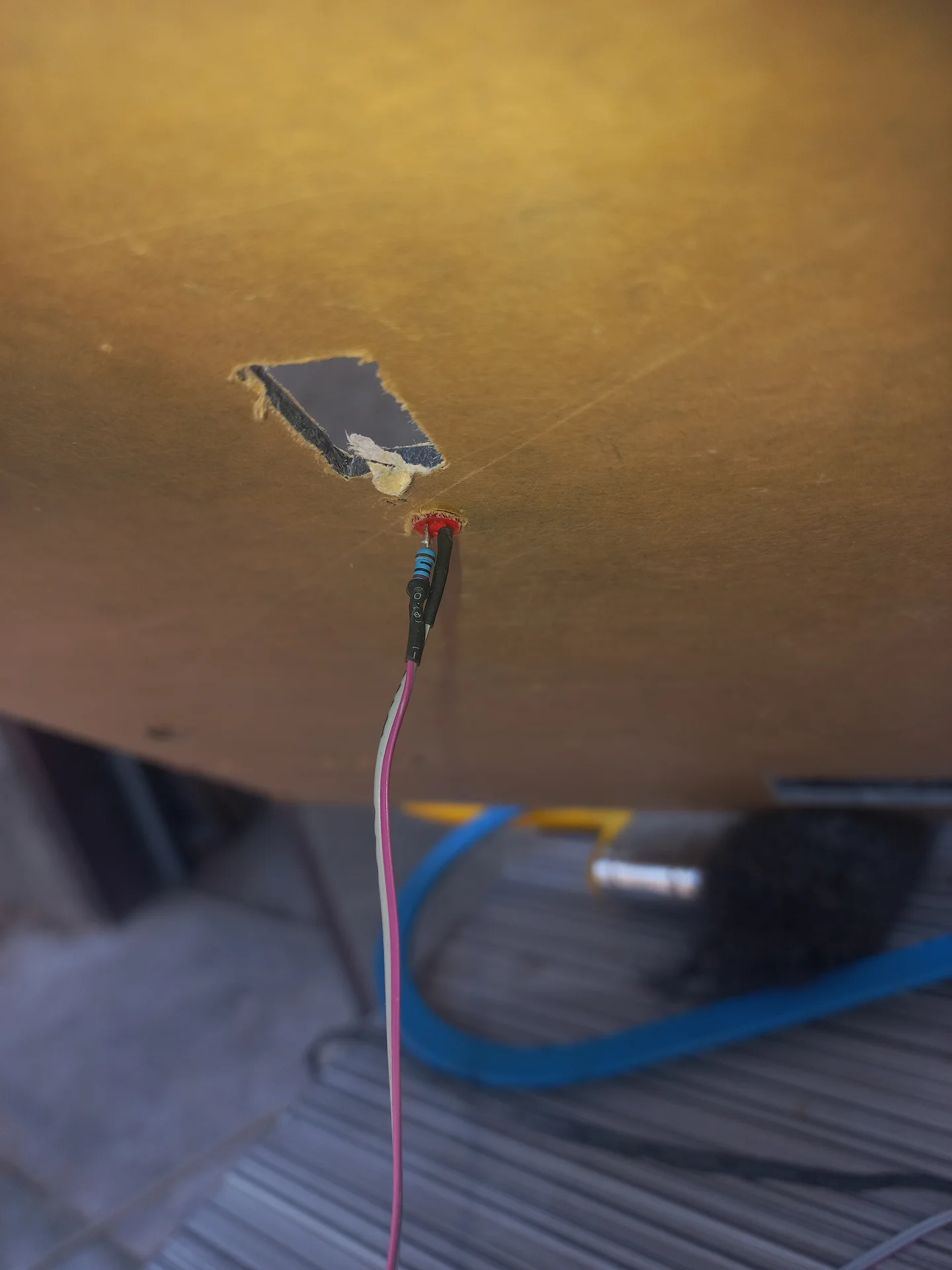 Back side of the panel showing an LED indicator pushed through its mounting hole with wires attached, alongside a rectangular cutout
