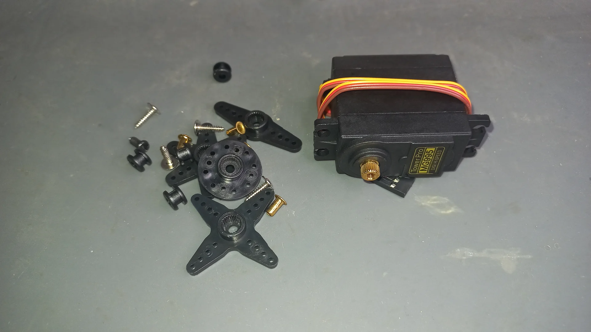 MG995 metal-gear servo motor with its complete set of servo horn accessories (cross disc, round disc, single arm, screws and grommets)