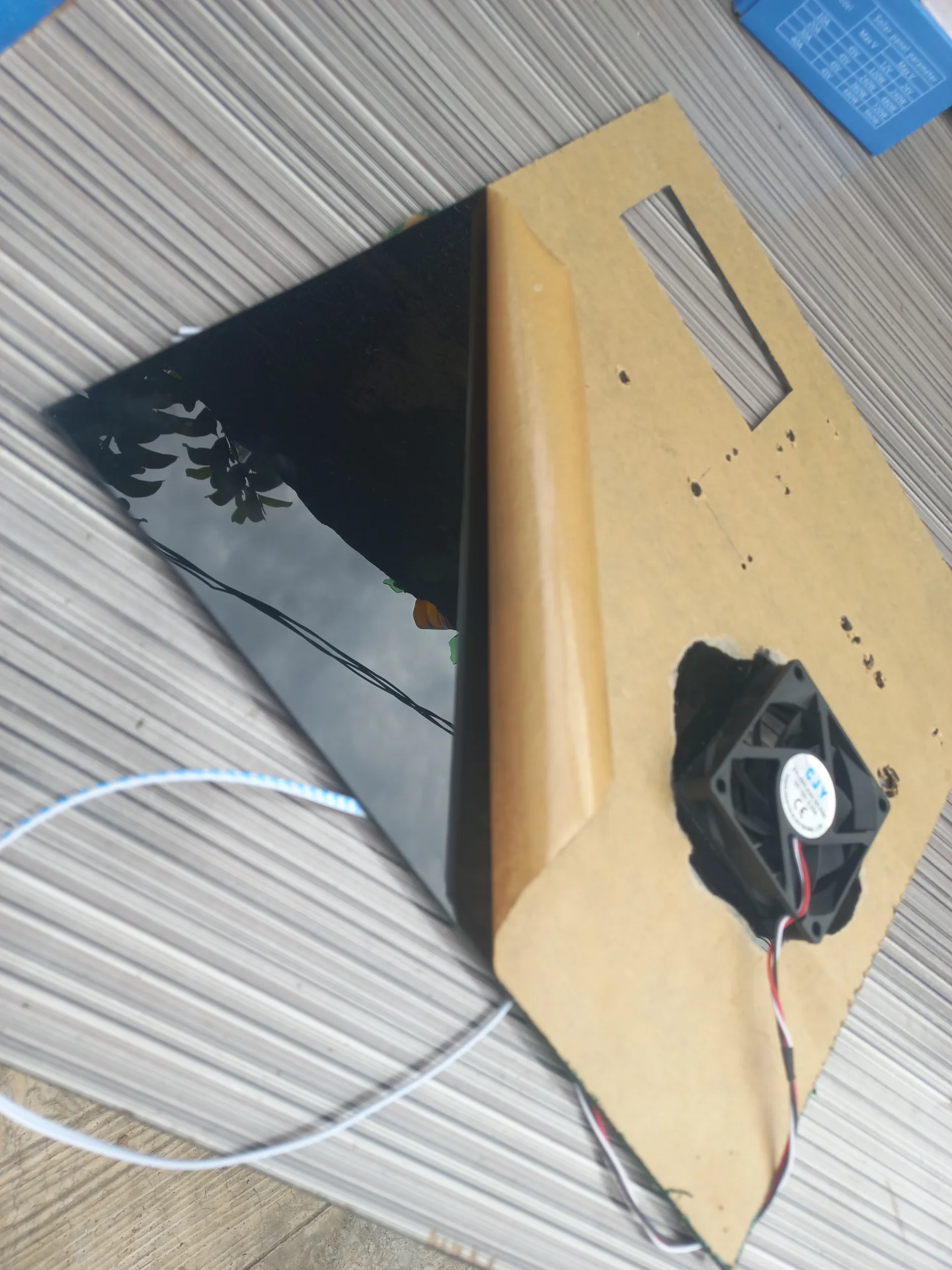 The black acrylic front panel and the hardboard backing with the cooling fan already mounted, laid side by side before being joined together