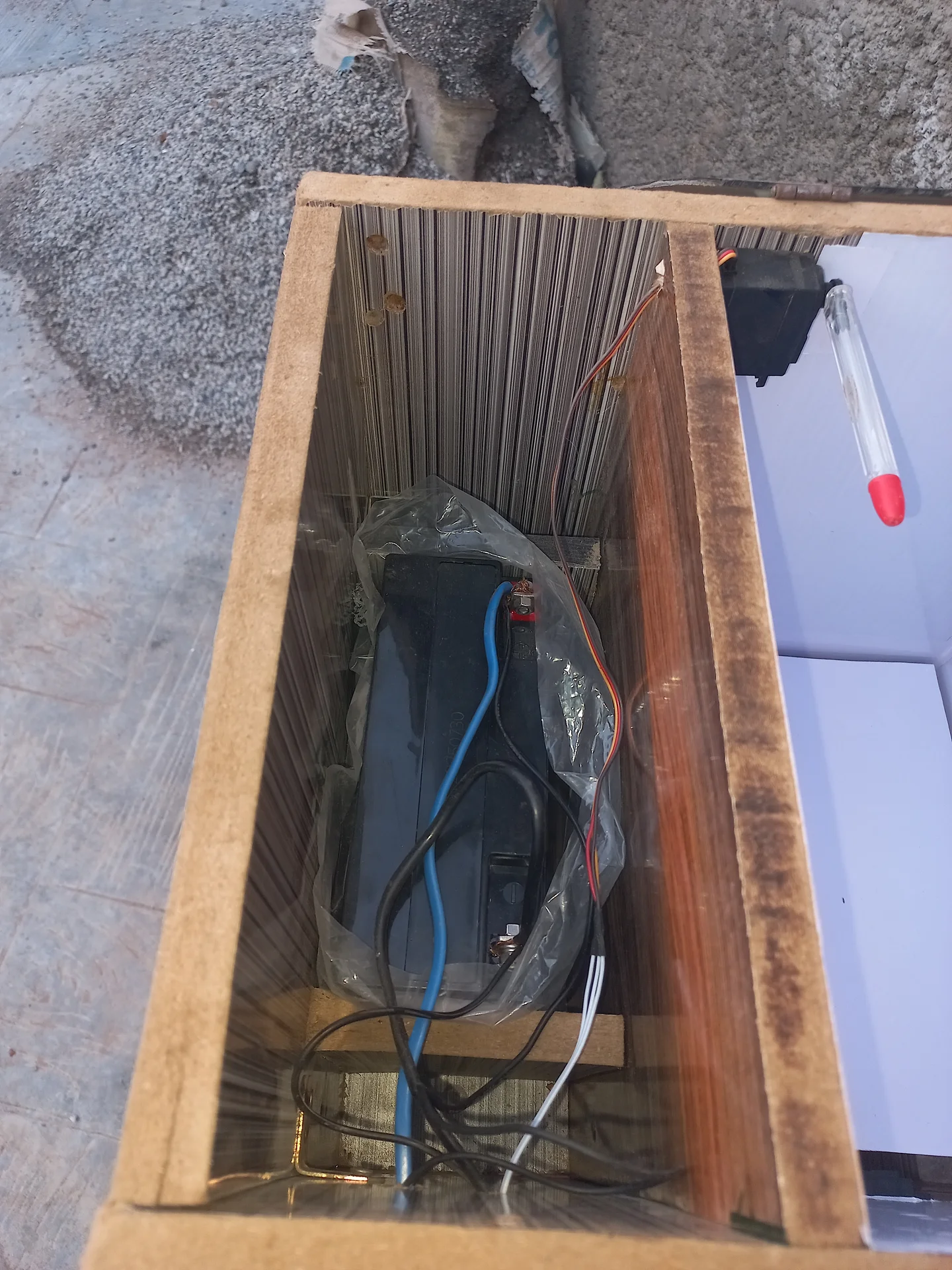 The battery inside the base compartment of the bin enclosure, with power cables connected