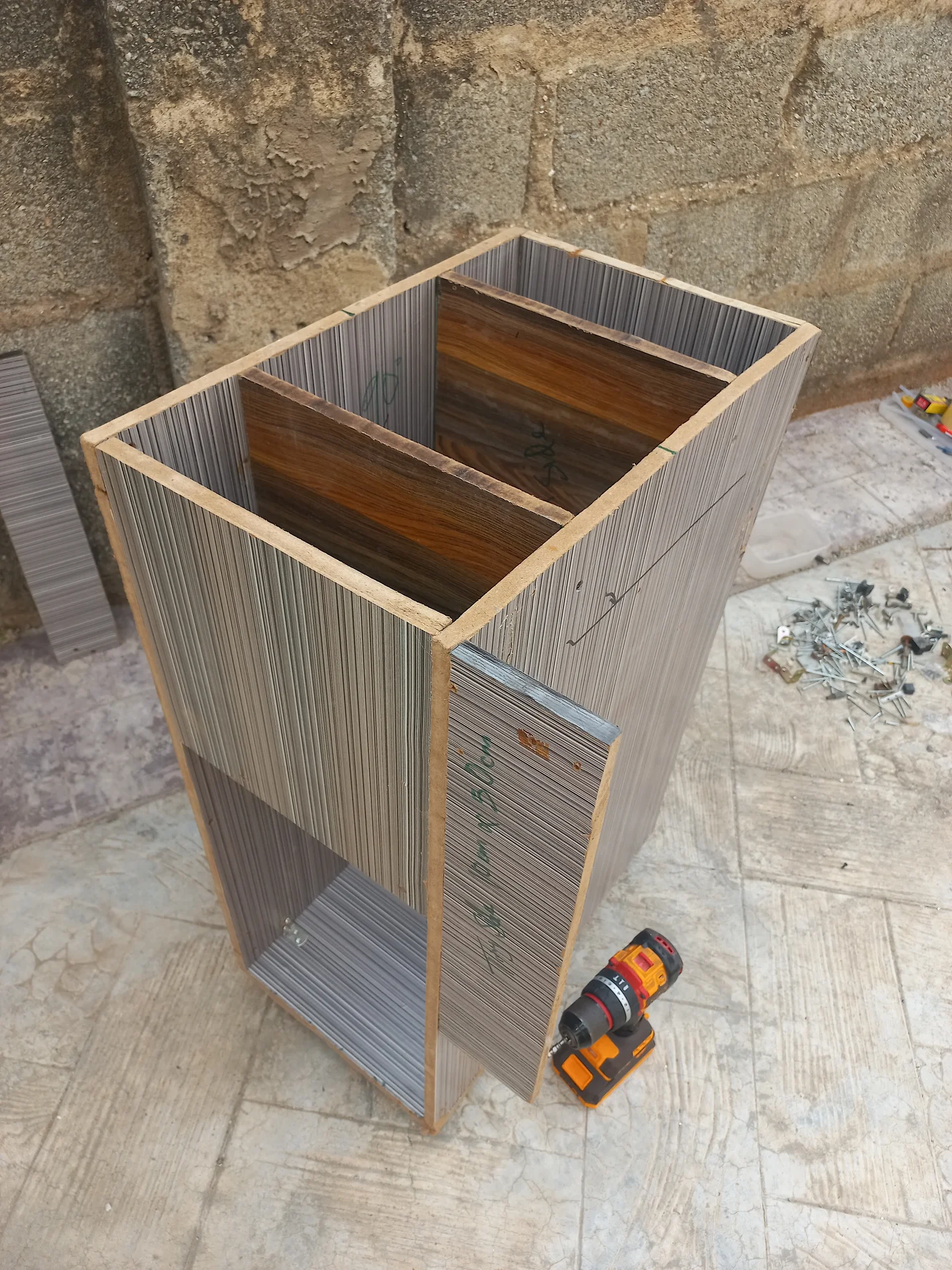 Three-quarter angled view of the bin showing the upper sorting section and the lower open storage bay, with corrugated panel walls and wooden framing
