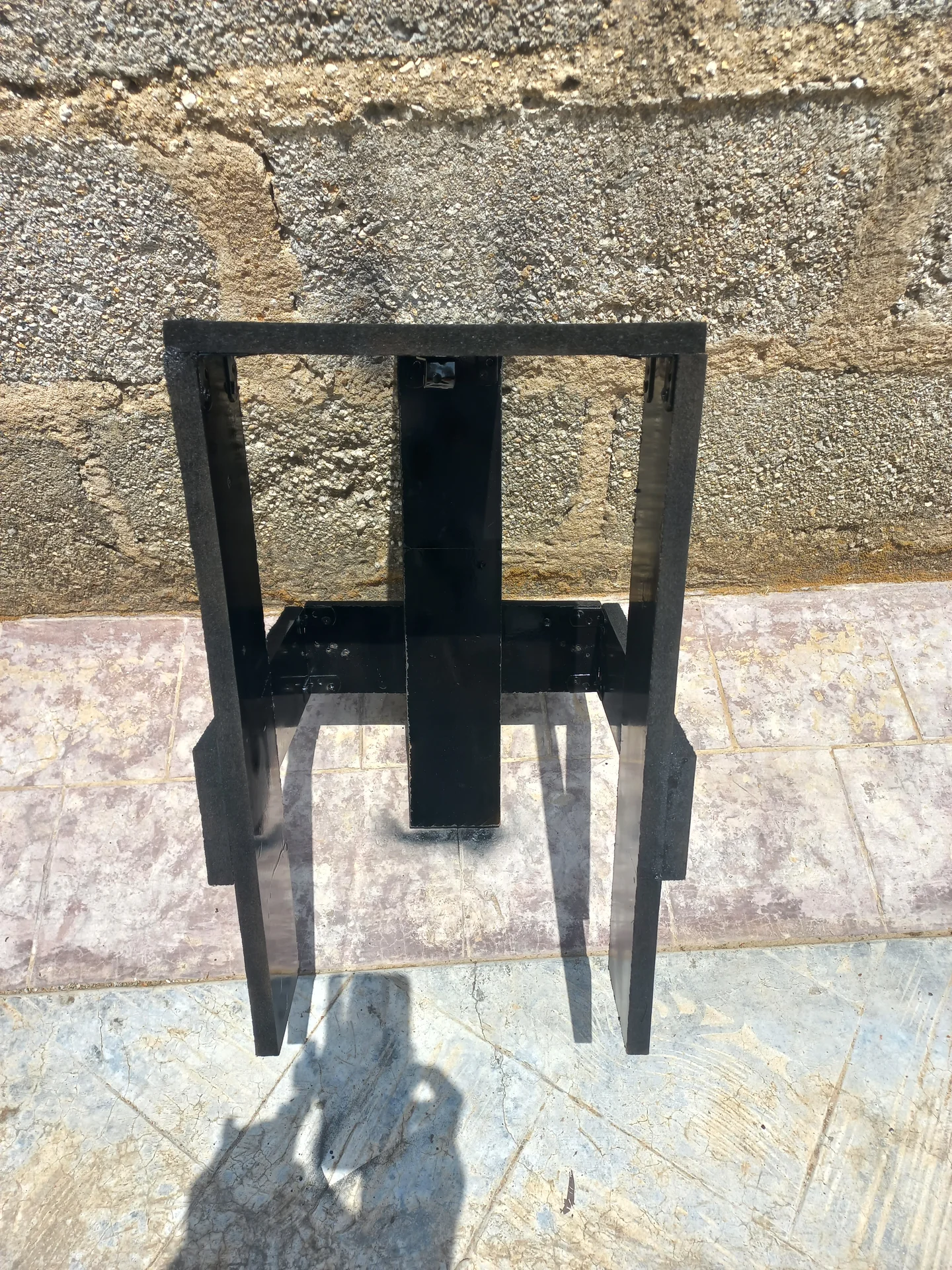 The black metal stand on its own, showing its rectangular frame construction with a central support column and base cross-brace