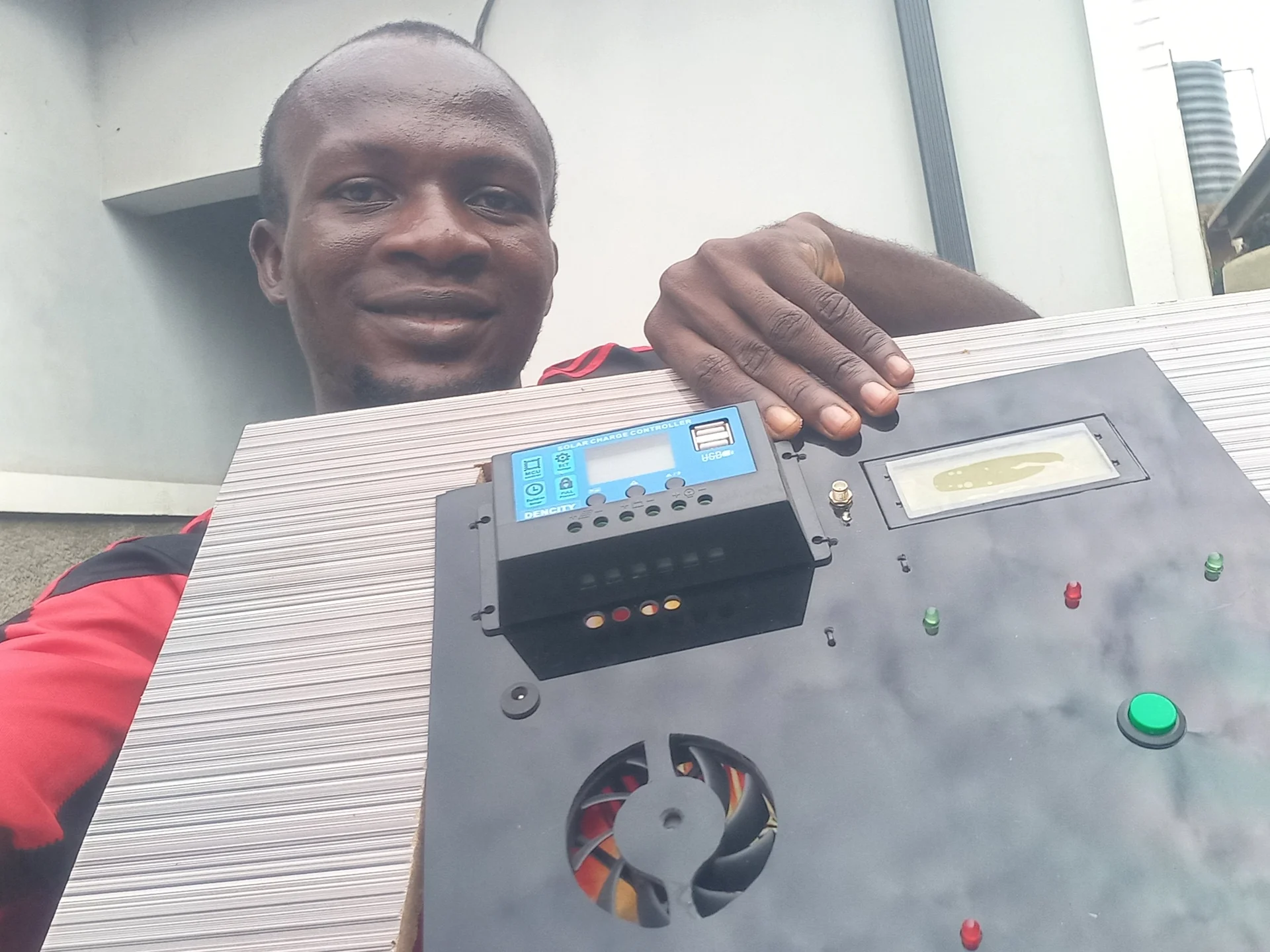 Builder holding the fully assembled control panel, showing the front face with all components mounted and labelled
