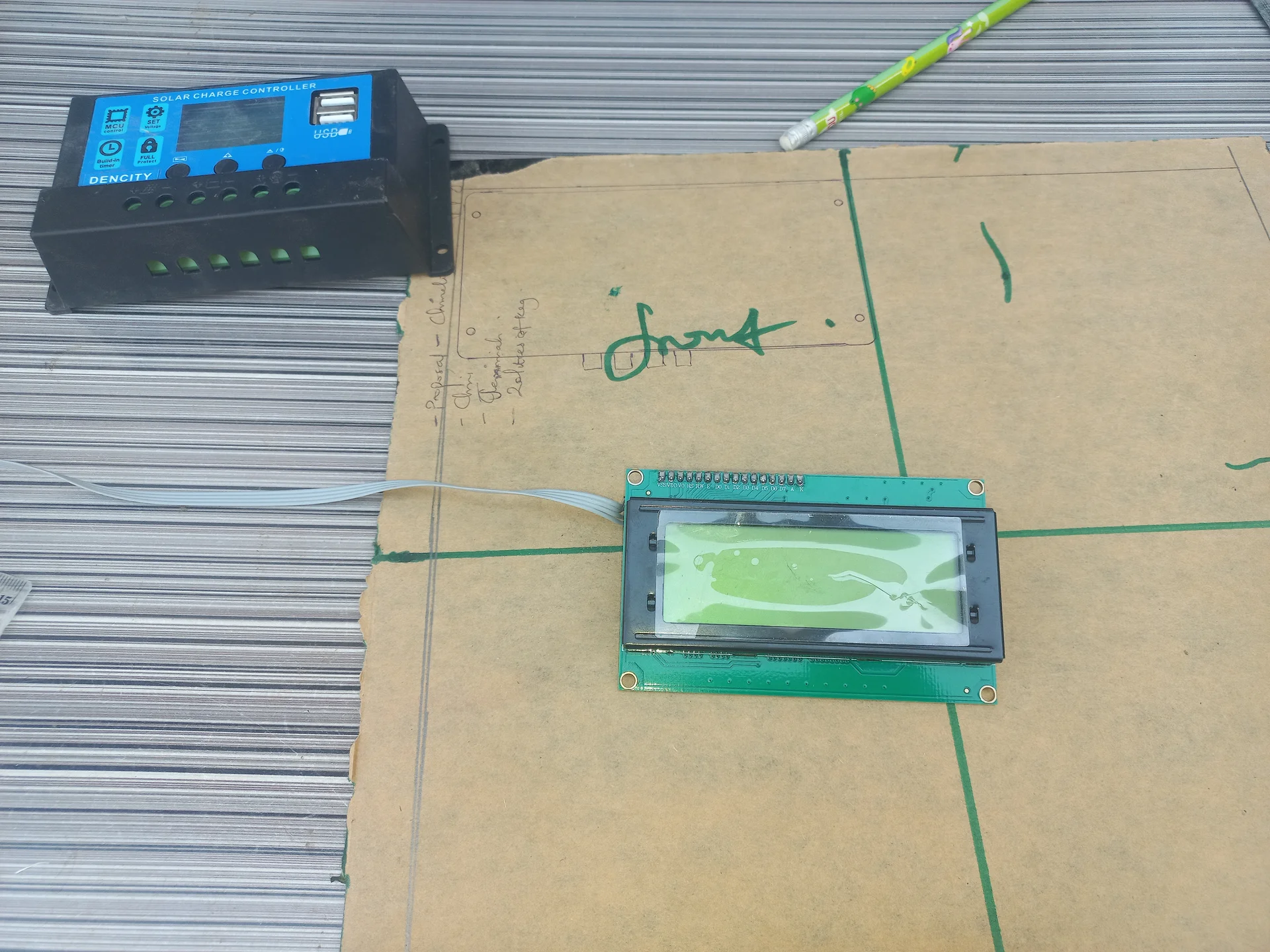 Charge controller and the LCD placed on a cardboard surface during a bench test before panel installation