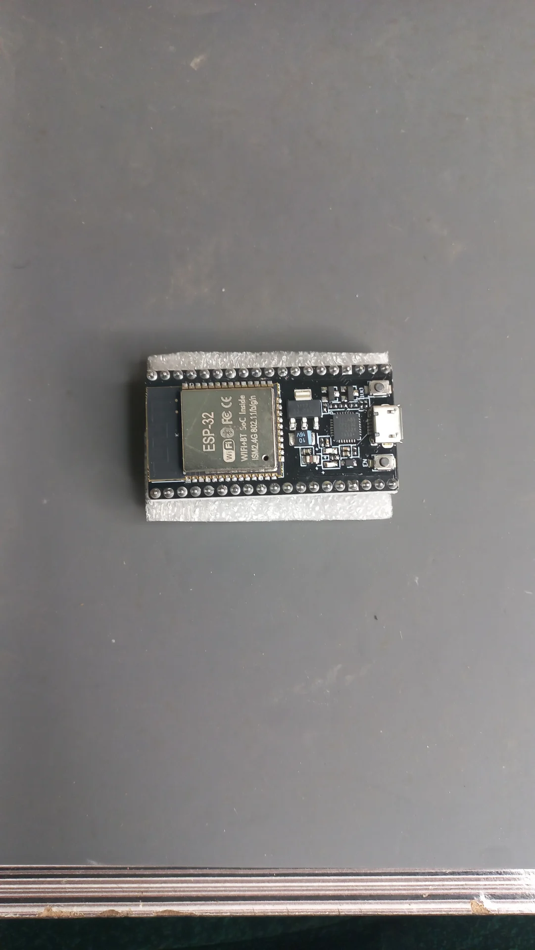 ESP32 DevKit board on a flat surface, showing the antenna, USB port and row of GPIO pins