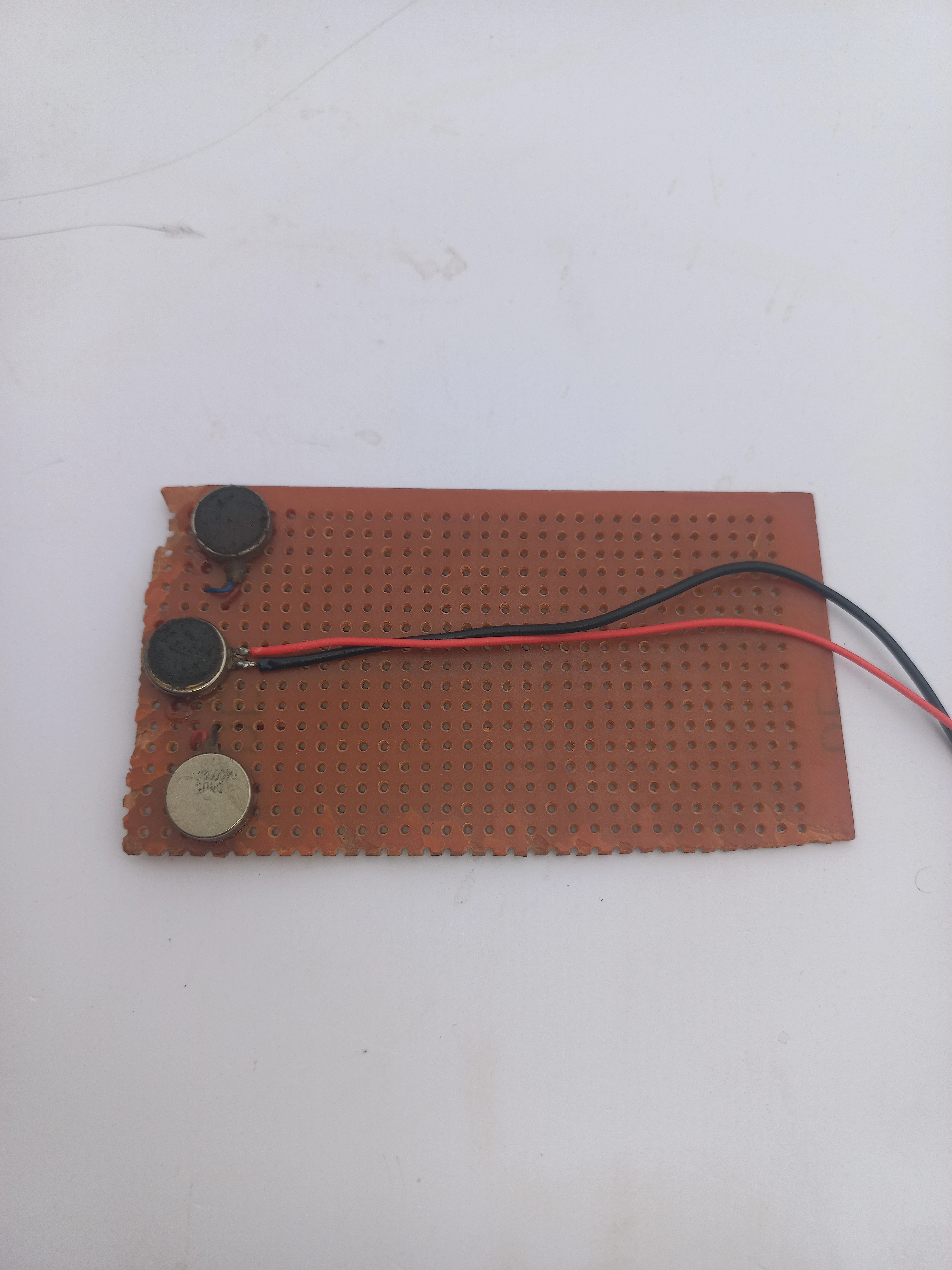 Haptic motor perfboard laid flat showing the copper side with solder joints