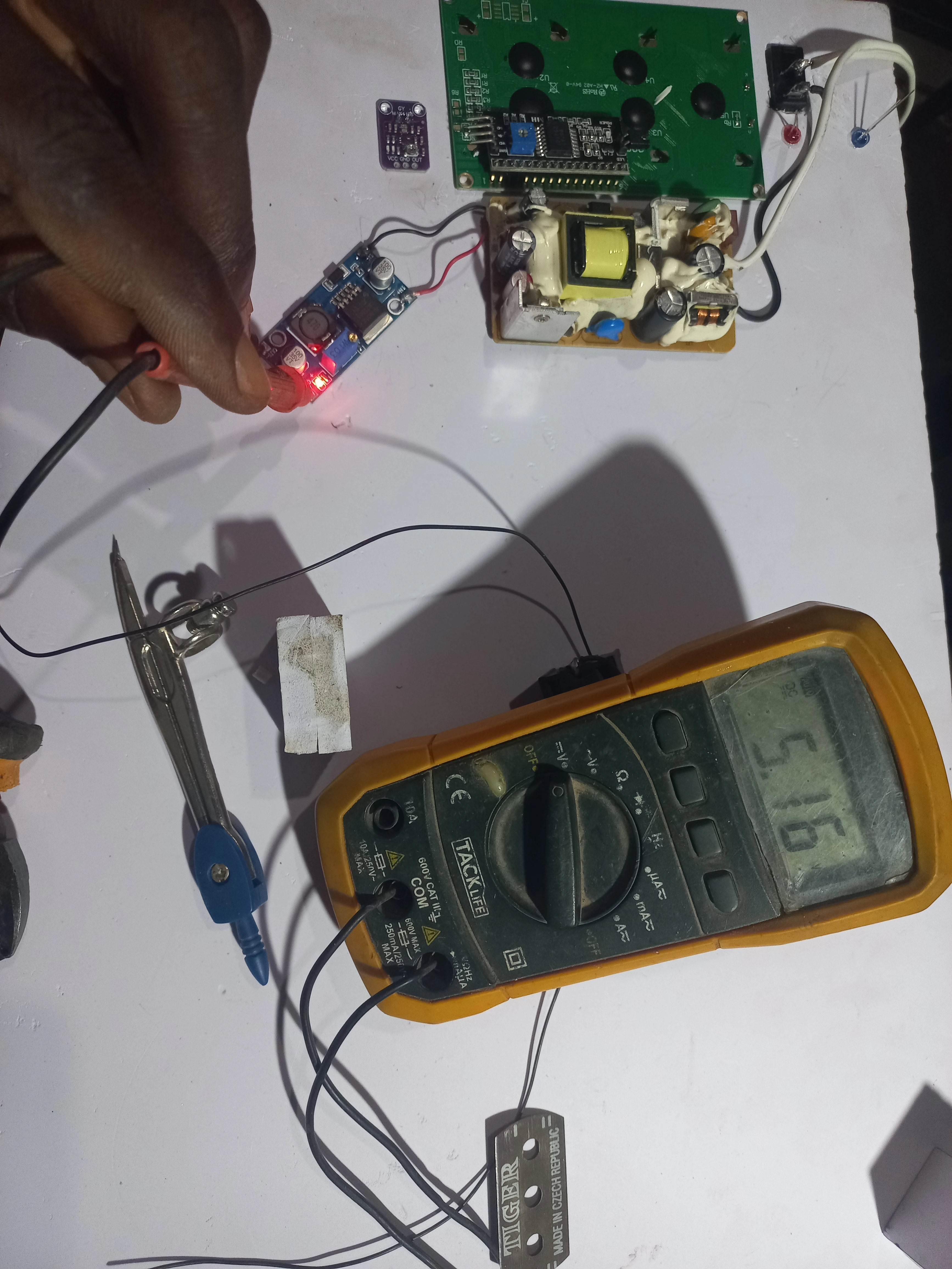 Multimeter probes on LM2596 output terminals confirming 5.16 V regulated supply for the road unit logic rail